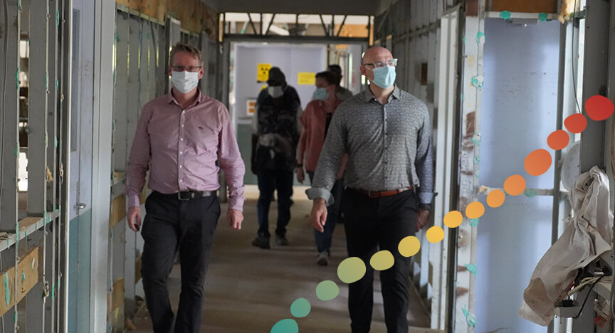 5 people walking through a corridor in a building