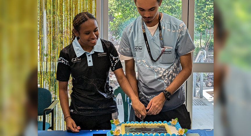 Two teenagers standing side by side, cutting a cake together.