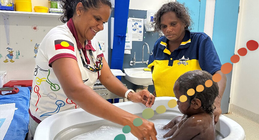 A person washing a baby in a tub, in a health clinic room.